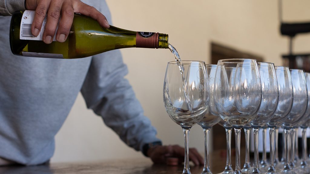 Wine being poured into a row of glasses