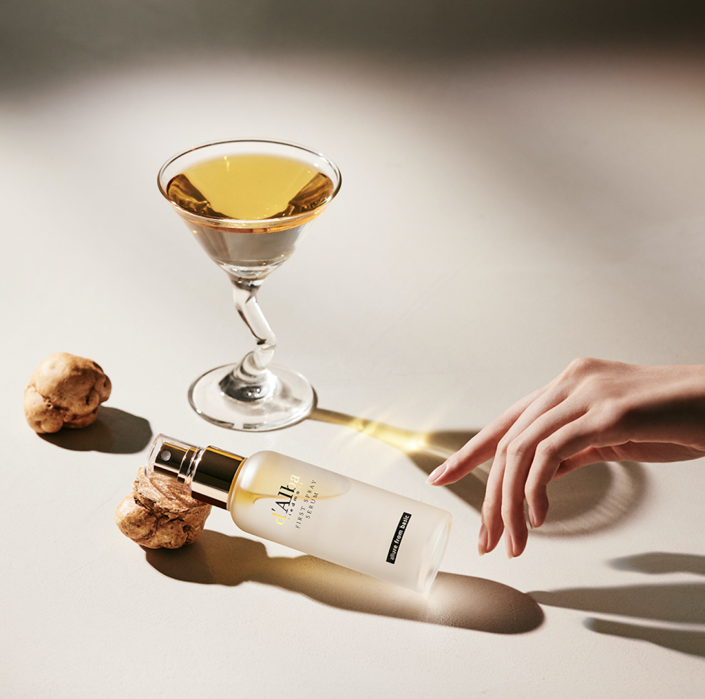 A bottle of d'Alba white truffle infused skin care serum on a white background with truffles.